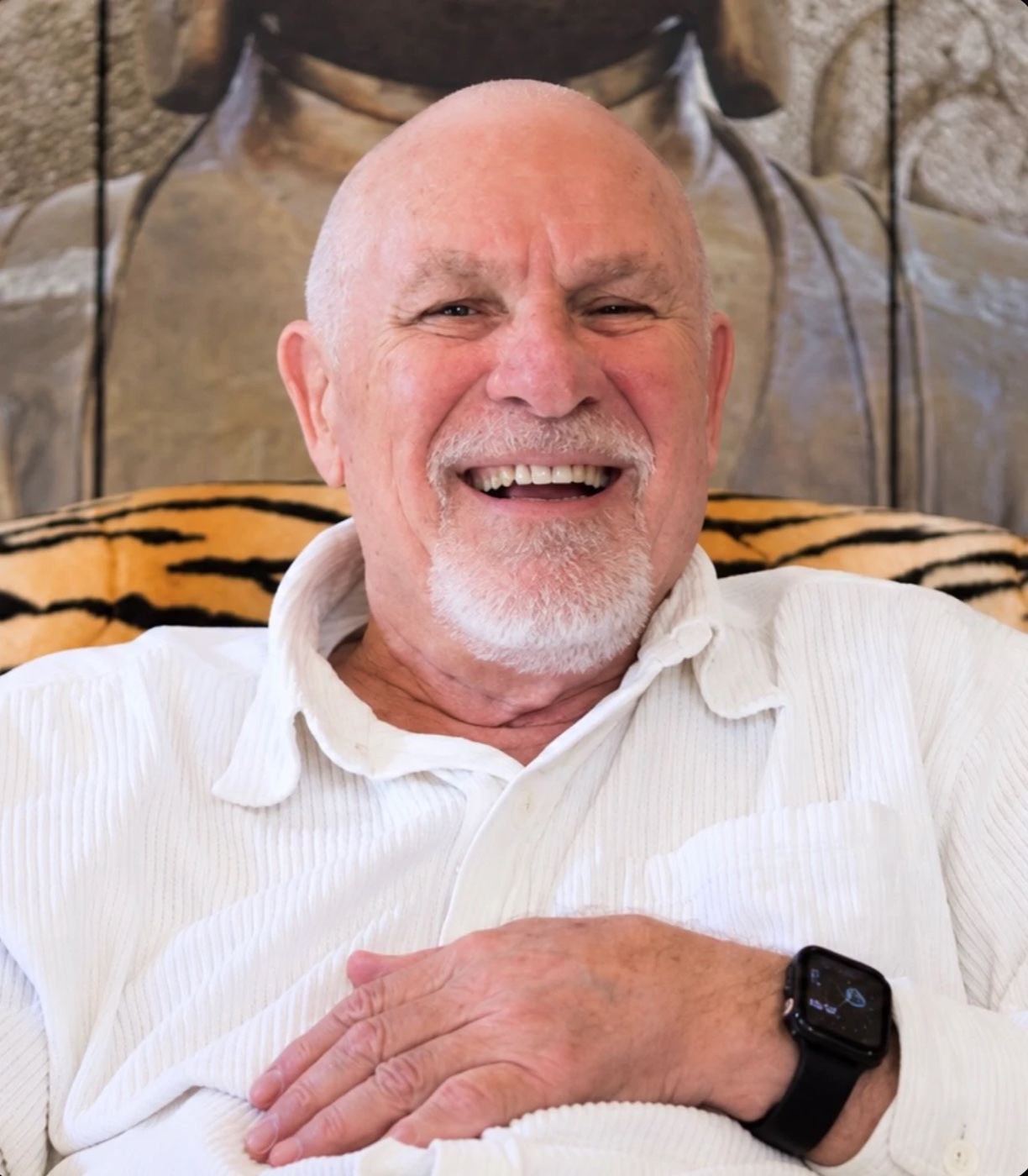 Vishrant laughing, seated in a tiger-print chair.