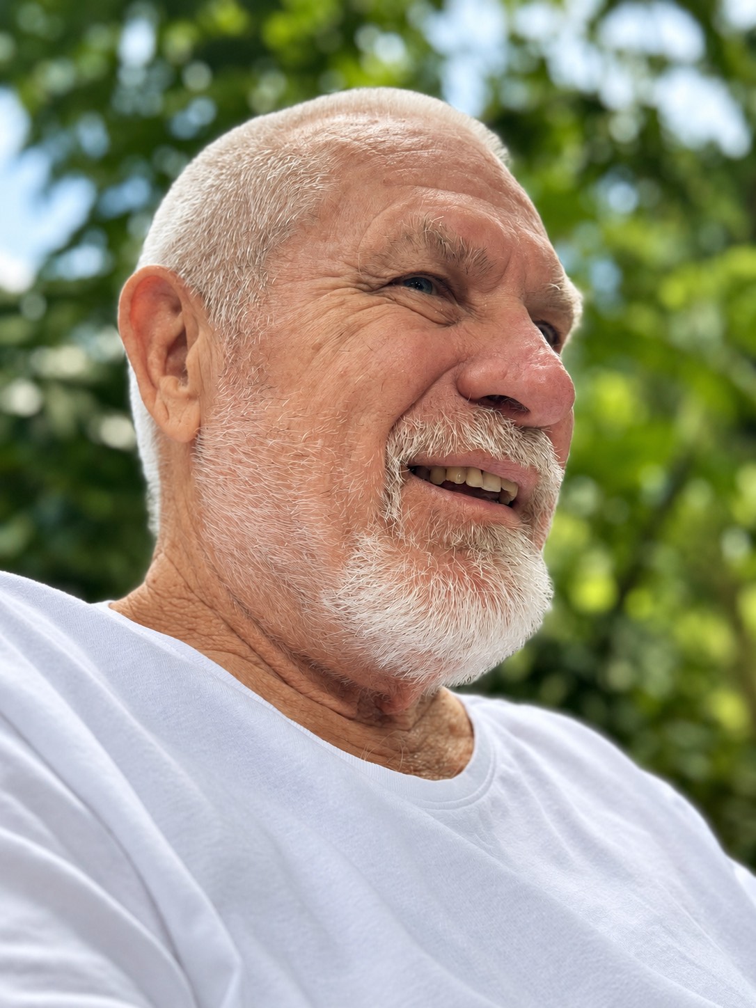 Vishrant smiling outdoors, green leaves behind him